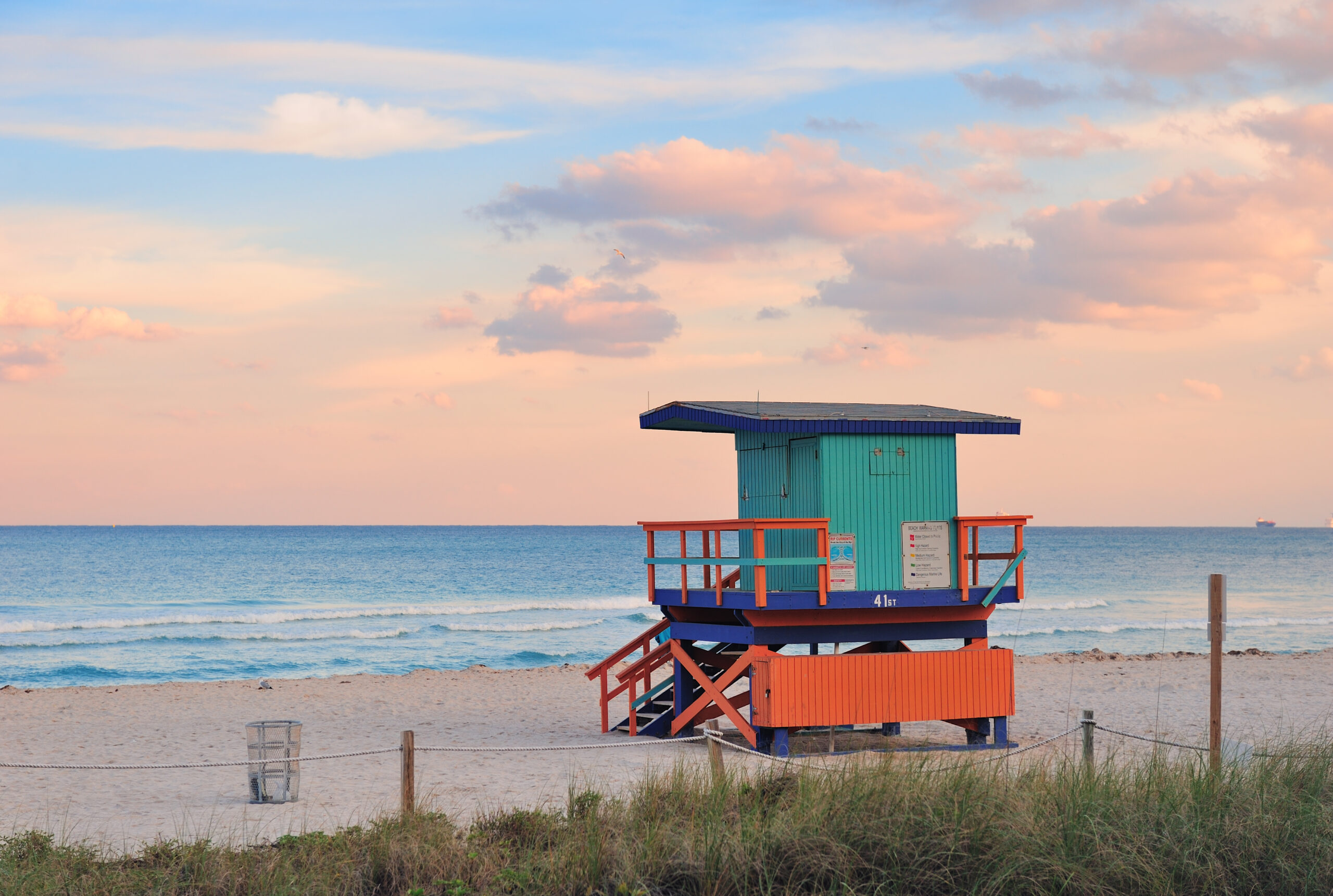 Miami South Beach sunset with lifeguard tower and coastline with colorful cloud and blue sky.